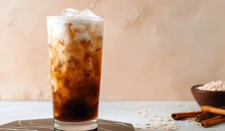 Brown sugar shaken espresso in a tall glass with oat milk swirl over ice