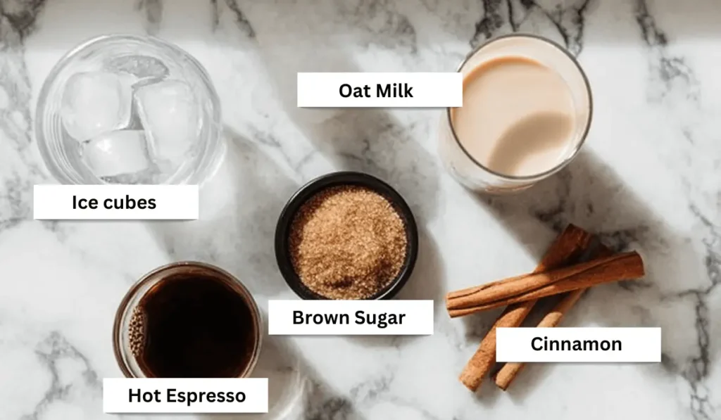 Flat lay of brown sugar shaken espresso ingredients: oat milk, brown sugar, hot espresso, ice cubes, and cinnamon sticks on marble background.