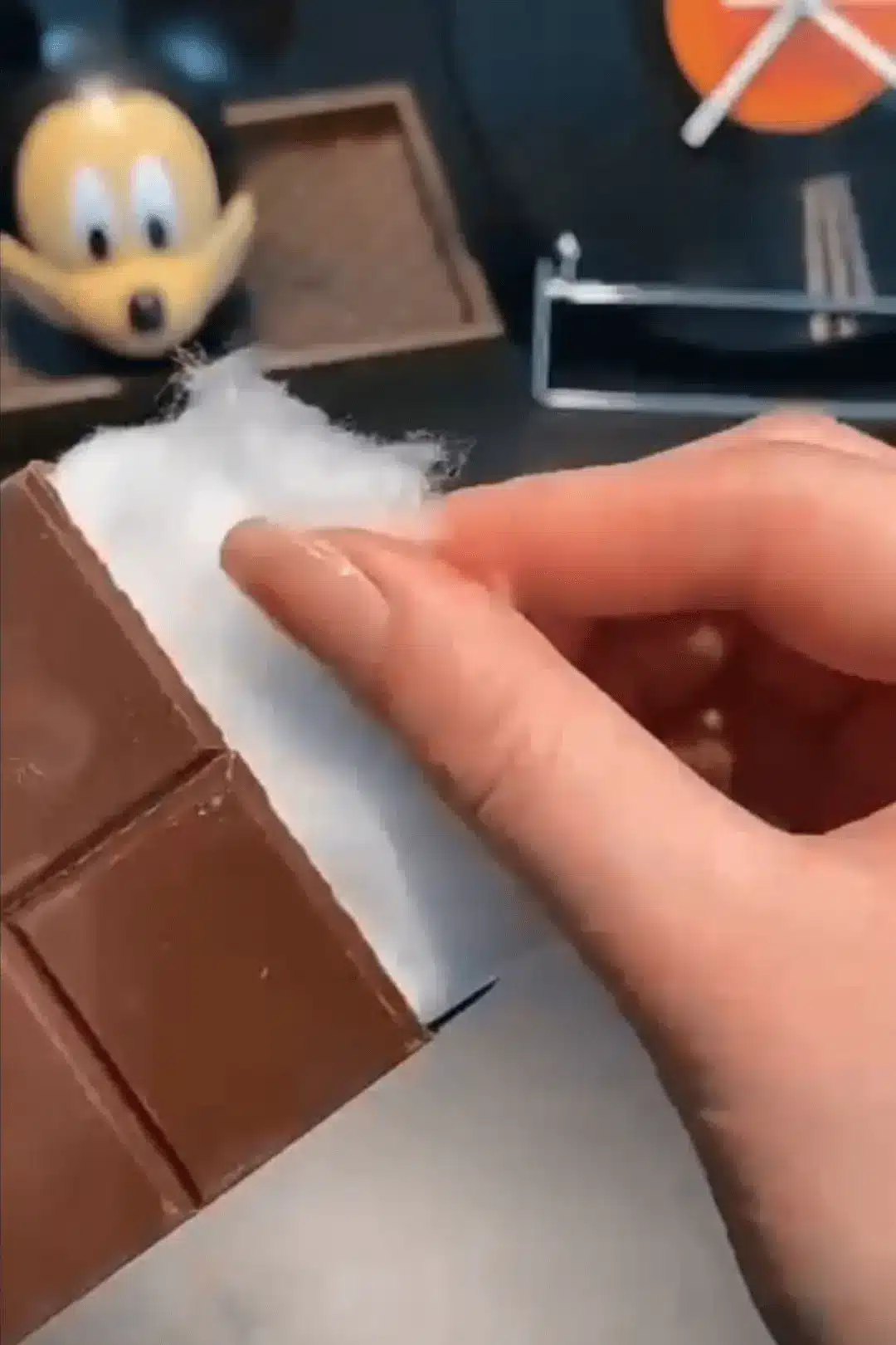 Close-up of hand separating cotton candy in chocolate
