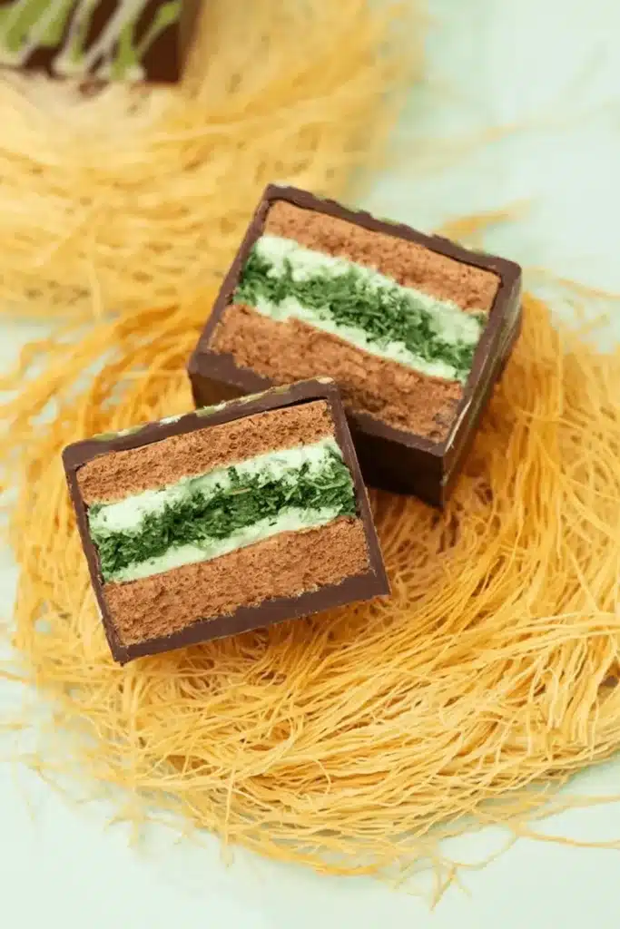 Sliced Dubai chocolate cake showing layers of pistachio kataifi filling, pistachio cream, and moist chocolate sponge
