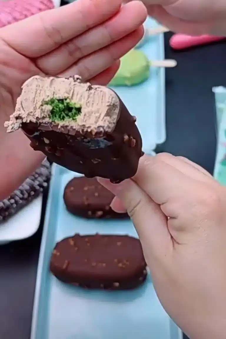 Bite shot of Dubai chocolate ice cream bar showing pistachio–kataifi filling and tahini chocolate ice cream