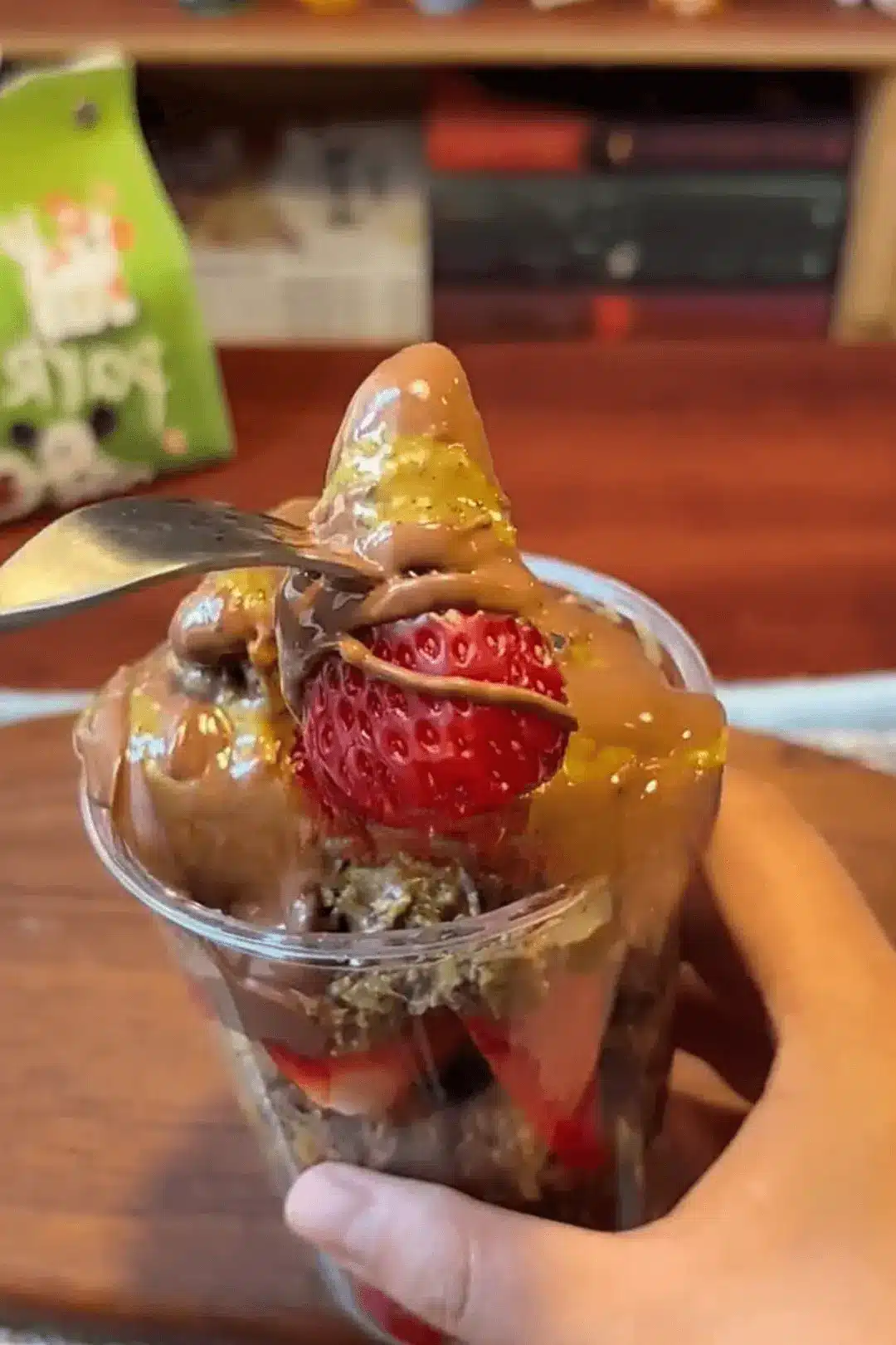 Spoon lifting strawberry covered in chocolate