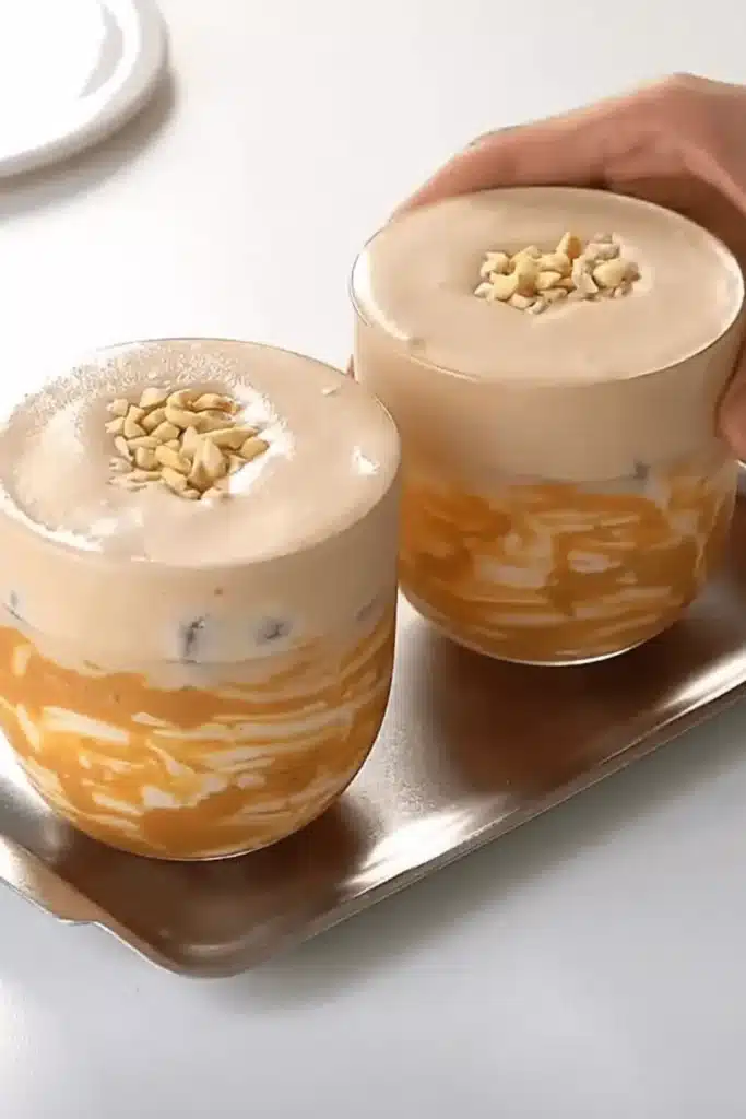 Two iced peanut butter lattes topped with chopped peanuts