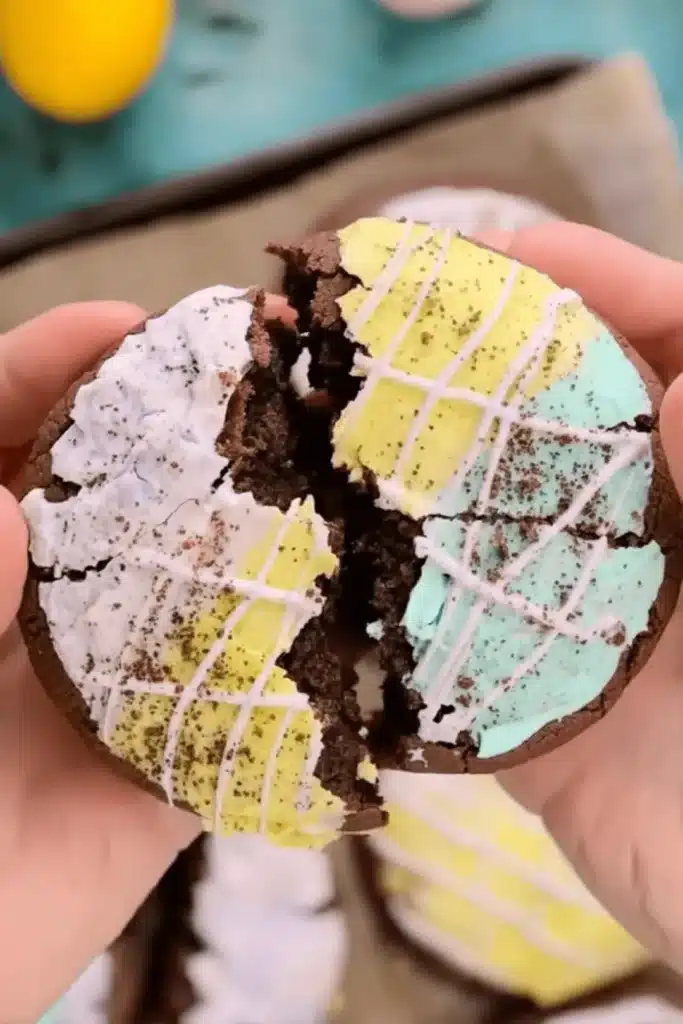 Hands holding a split Moonbeam Ice Cream Crumble Cookie with marshmallow, lemon, and berry frosting