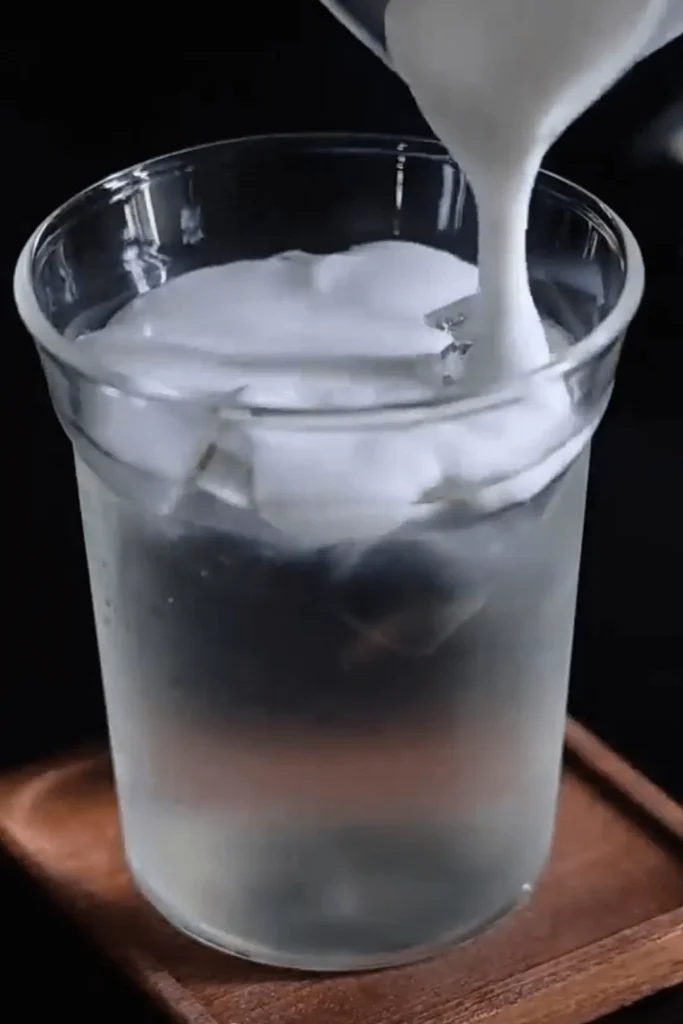 Creamy cloud layer pouring over ice and coconut water for Coconut Cloud Coffee