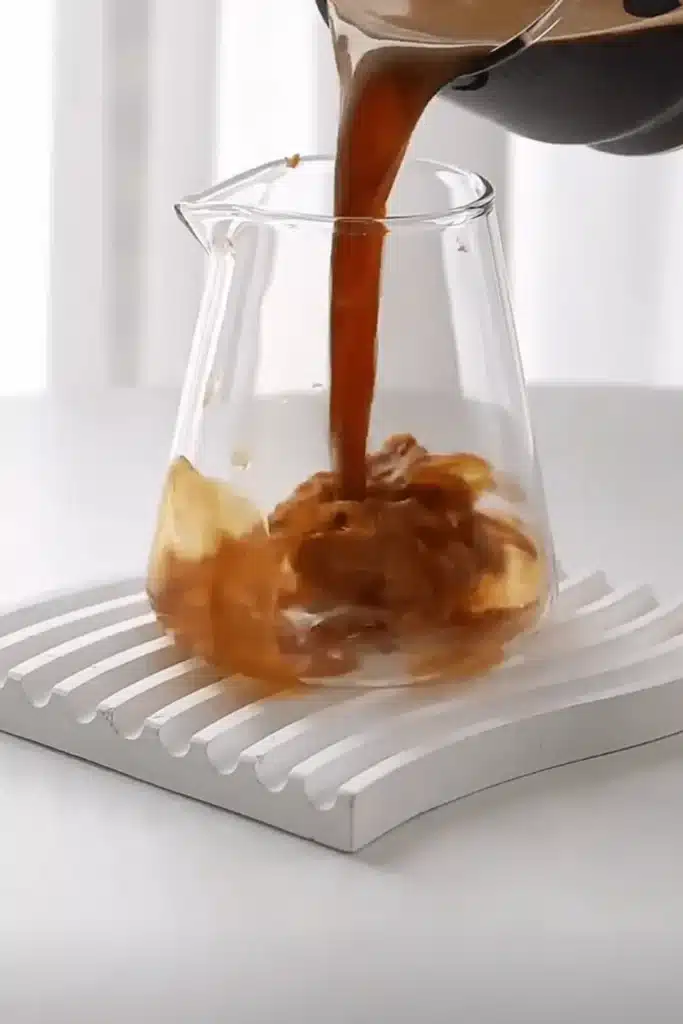 Pouring espresso over creamy peanut butter in a glass to make a latte