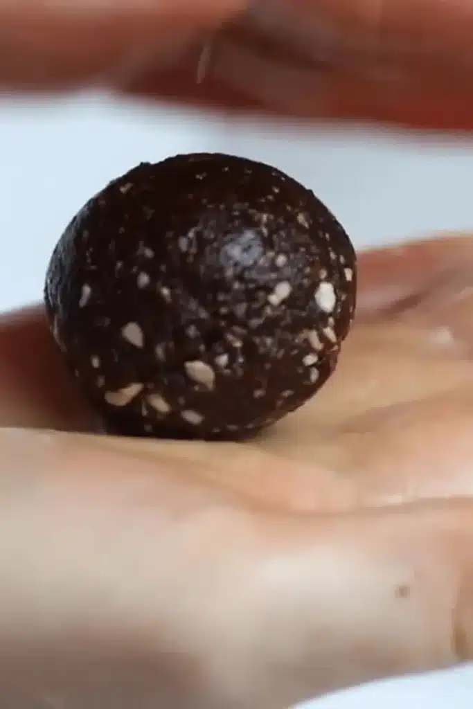 Rolling a homemade date brownie ball with almonds and cocoa
