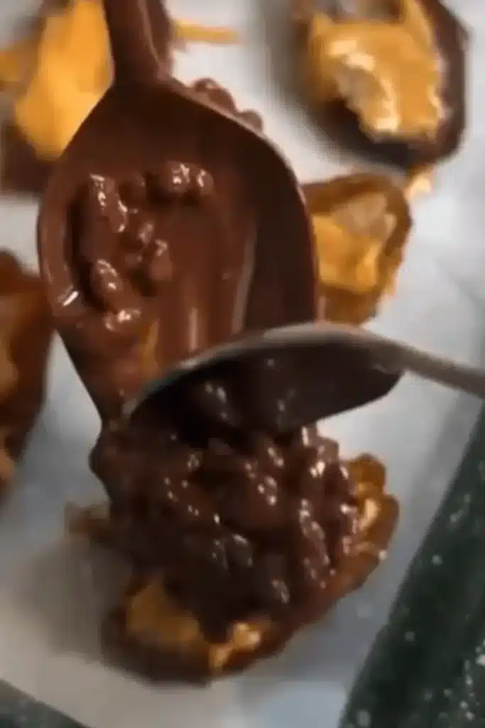 Spoonful of melted chocolate with puffed rice being poured over a peanut butter-stuffed date