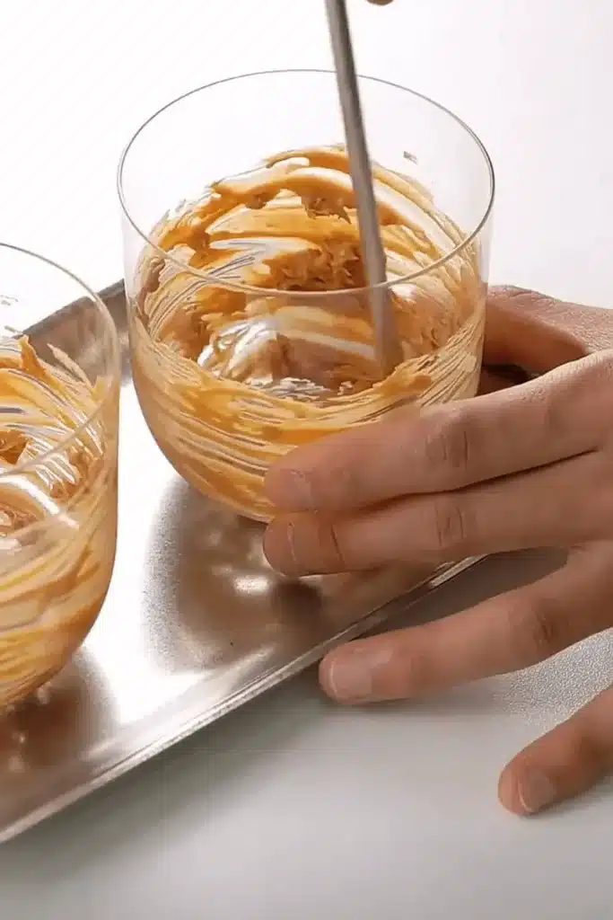 Spreading peanut butter on the sides of a glass for iced peanut butter latte