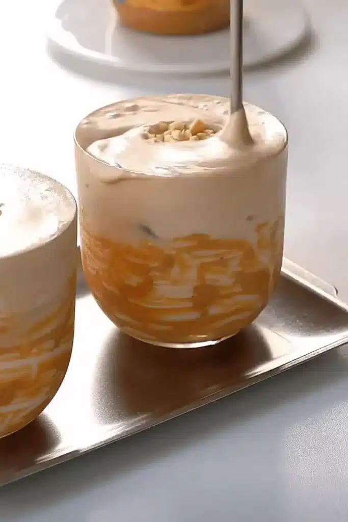Stirring an iced peanut butter latte with a spoon to blend creamy layers