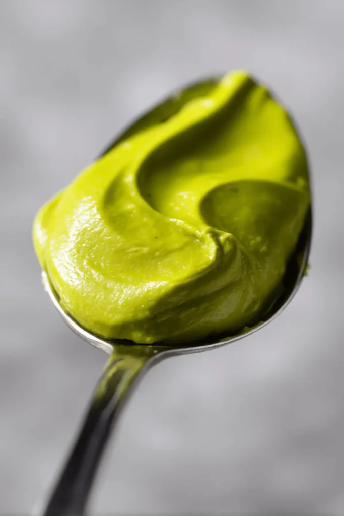 Thick and creamy homemade pistachio butter on a spoon, vibrant green and smooth