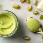 Pistachio cream recipe in a glass jar with spoon and chopped pistachios